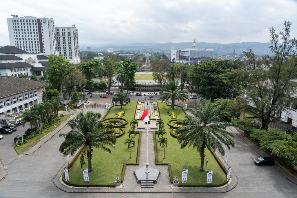 A vibrant city park with palm trees and national flags from above.